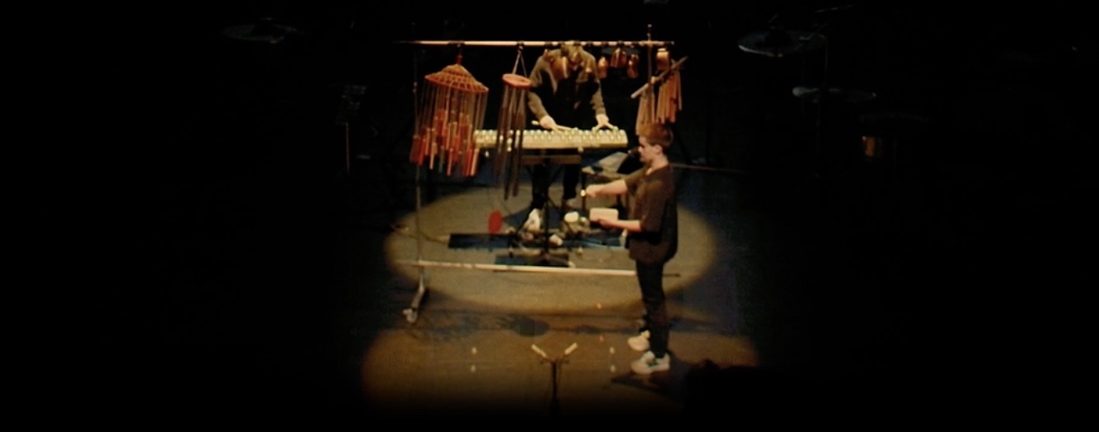 Performers on a dark stage under a spotlight